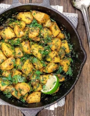 Batata harra with a lime wedge for garnish in a skillet.