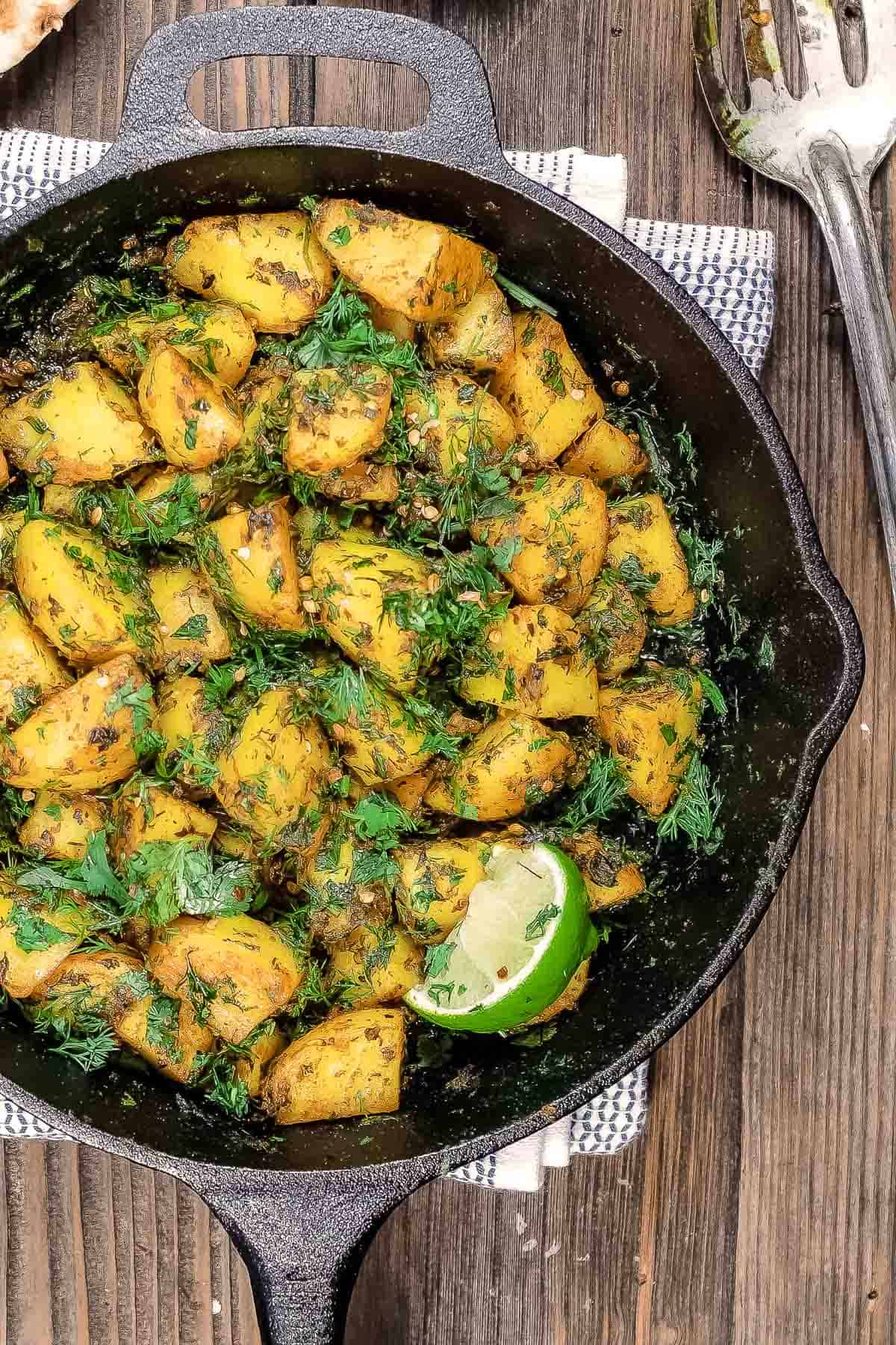 Batata harra with a lime wedge for garnish in a skillet.