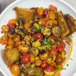 simple cherry tomato salad on a plate with fried sourdough.