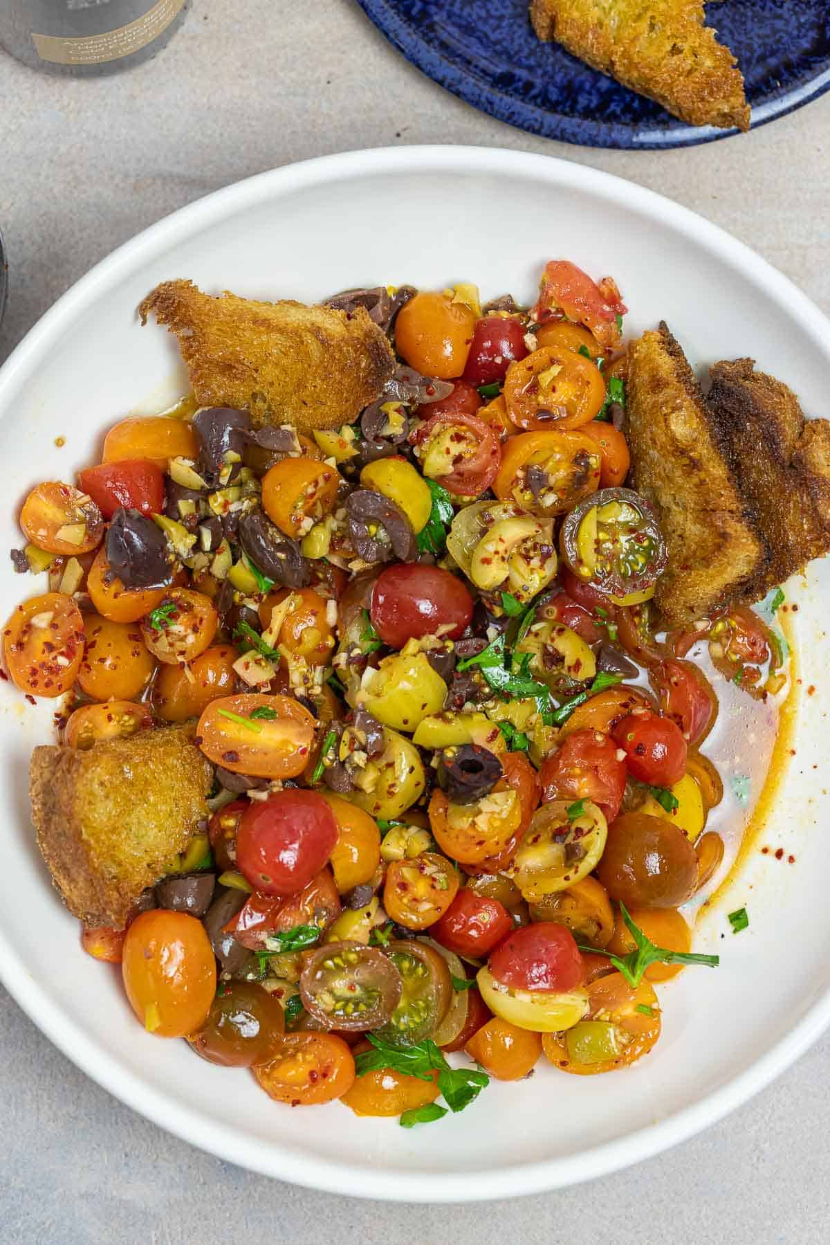 simple cherry tomato salad on a plate with fried sourdough.