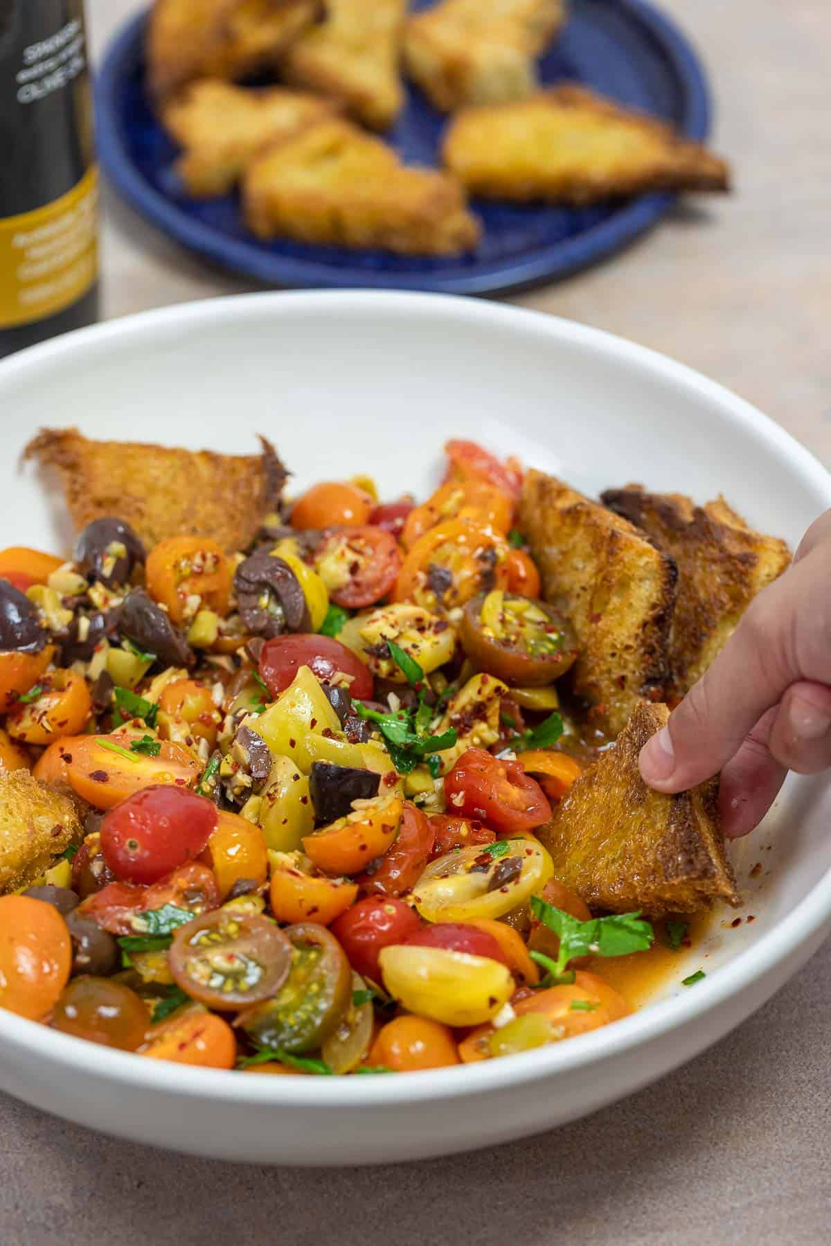 marinated tomato salad on a white plate with fried sourdough.