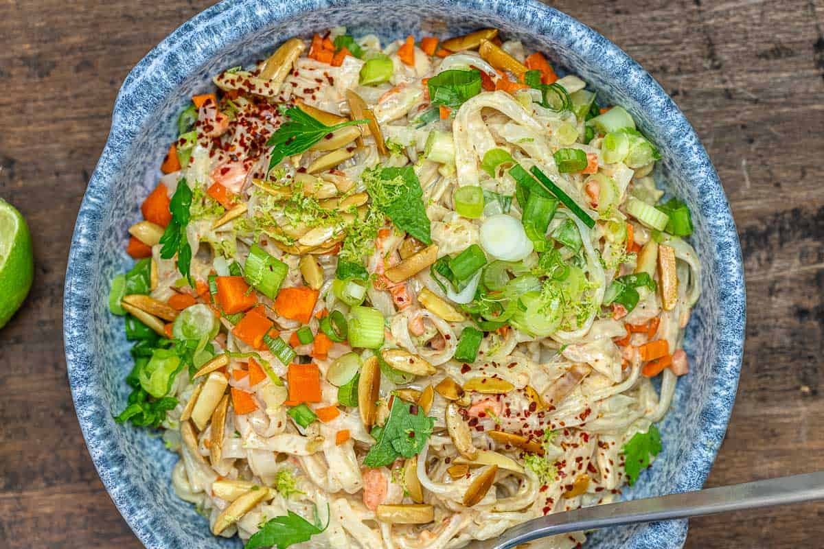 noodle salad with green onions, carrots, slivered almonds, and more in a blue bowl.