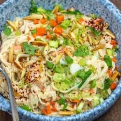 rice noodle salad with vegetables and tahini dressing in a blue bowl.