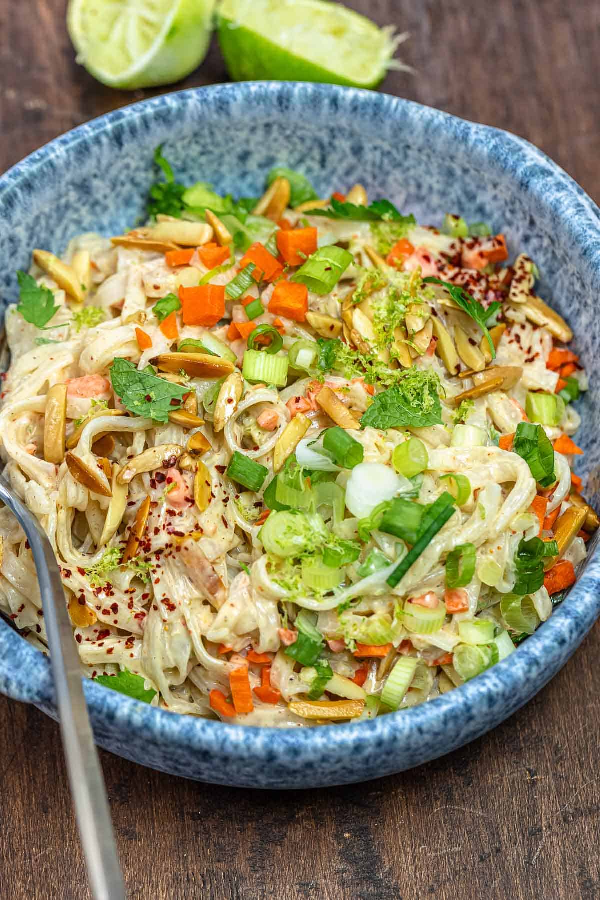 rice noodle salad with vegetables and tahini dressing in a blue bowl.