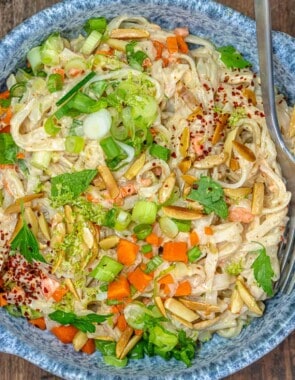 noodle salad with vegetables and slivered nuts in a blue bowl with a fork.
