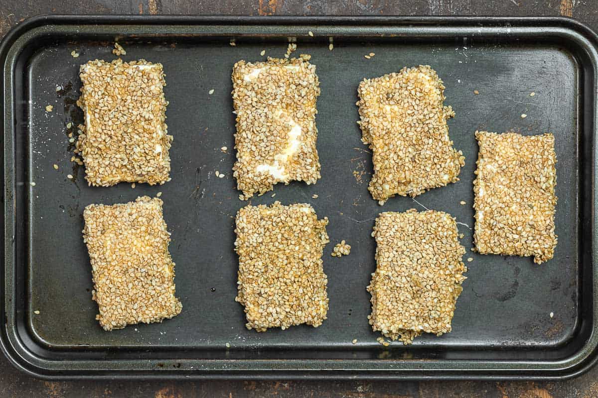 feta cheese on a baking sheet after being coated with sesame seeds. Ready for frying.