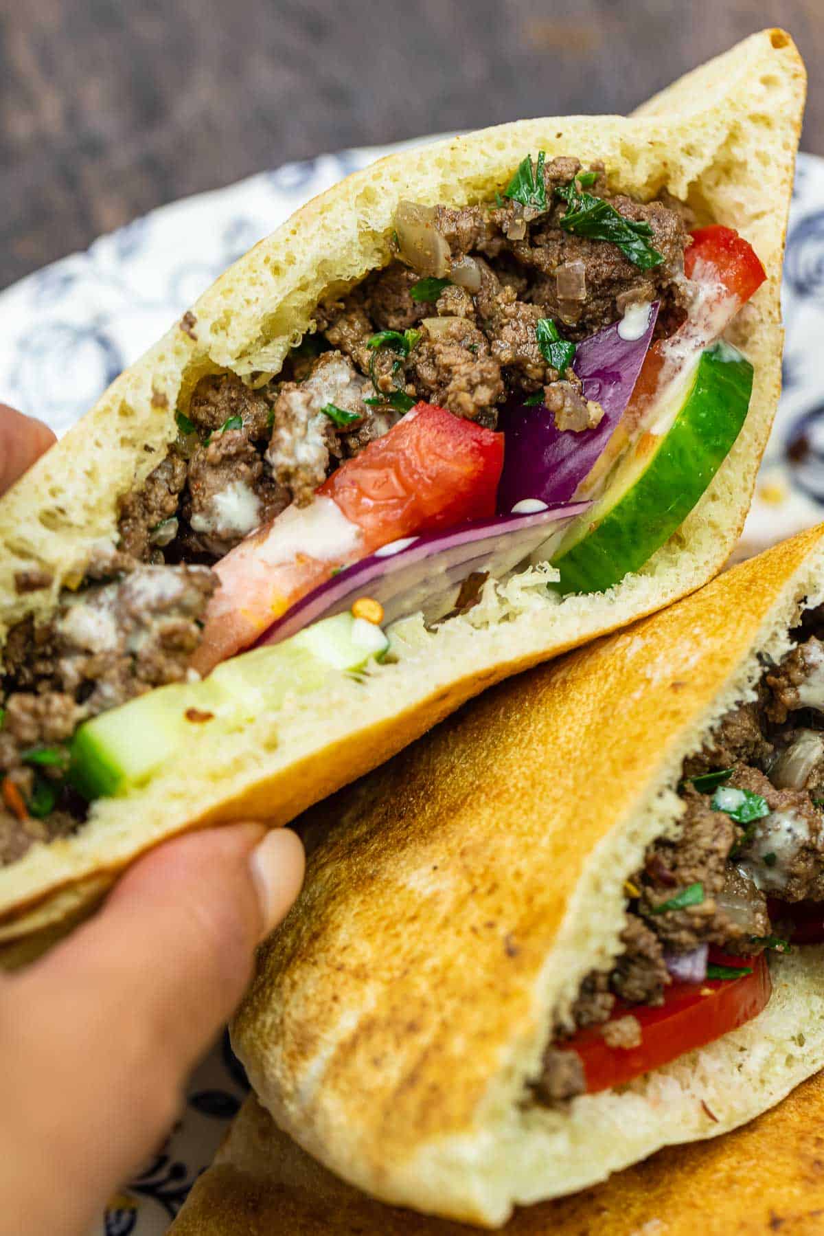 Middle Eastern ground beef pita sandwich with cucumber, tomatoes, red onion, and tahini sauce.