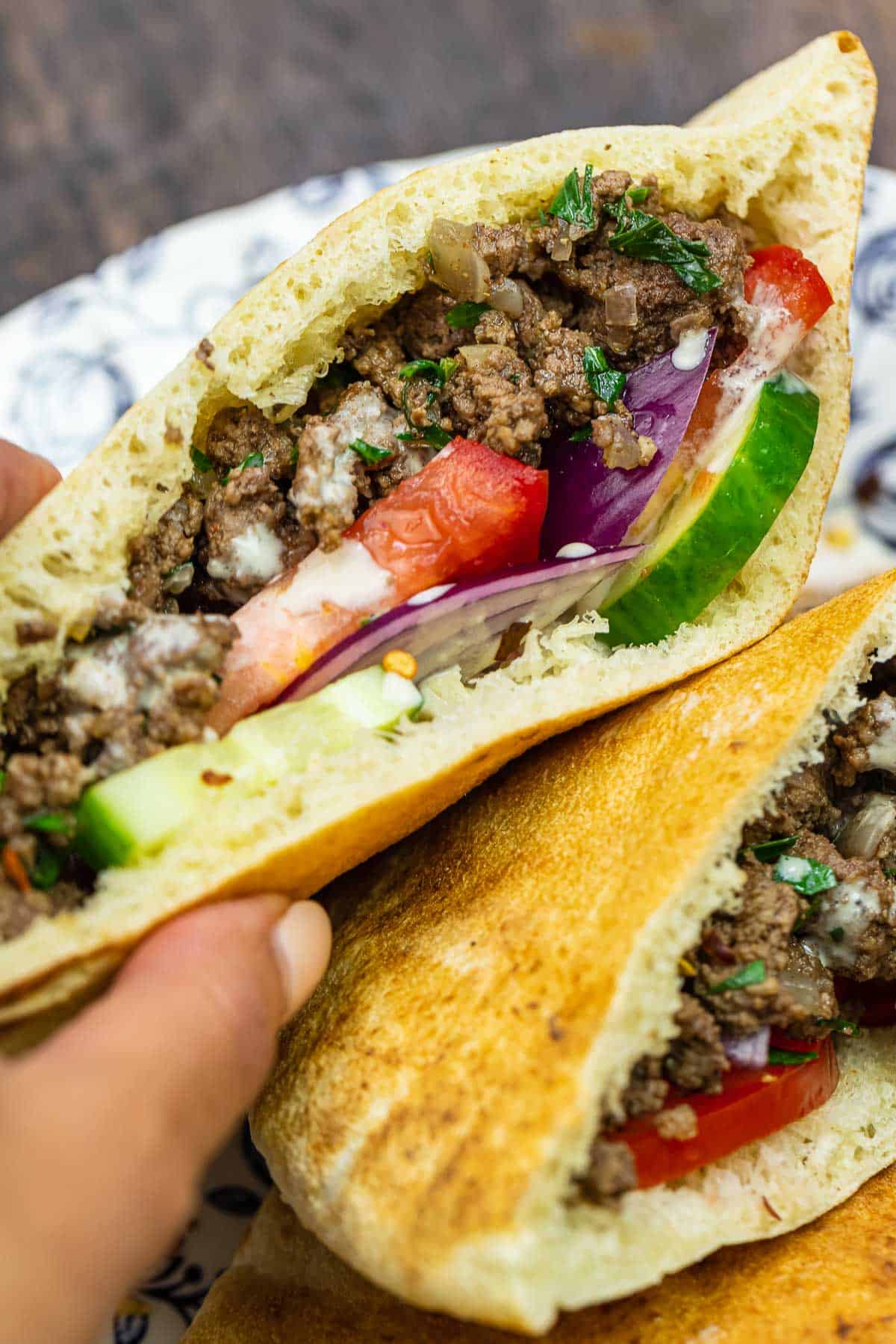 Middle Eastern ground beef pita sandwich with cucumber, tomatoes, red onion, and tahini sauce.