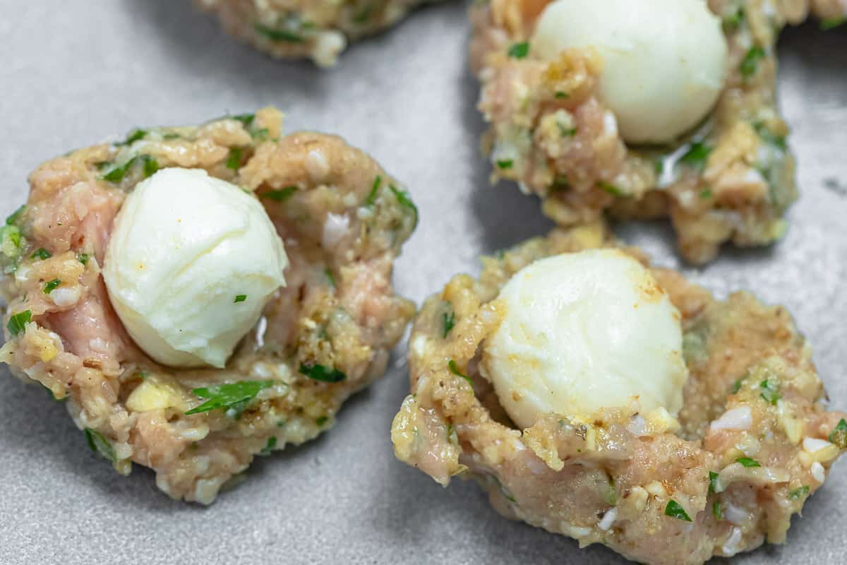 step image showing a baby mozzarella ball placed in the chicken meatball mixture.