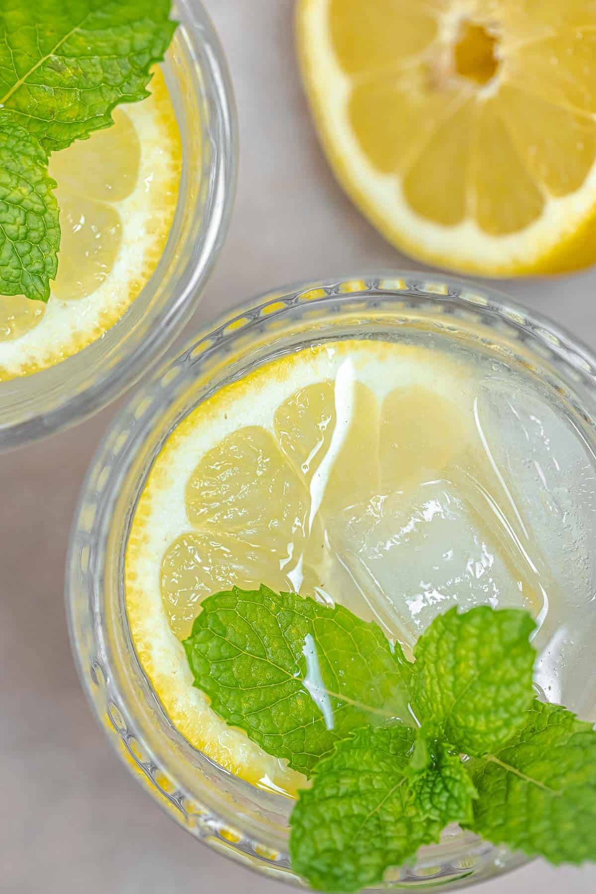 cocktail with ouzo, fresh lemon juice, muddled mint leaves, and ice in glasses.