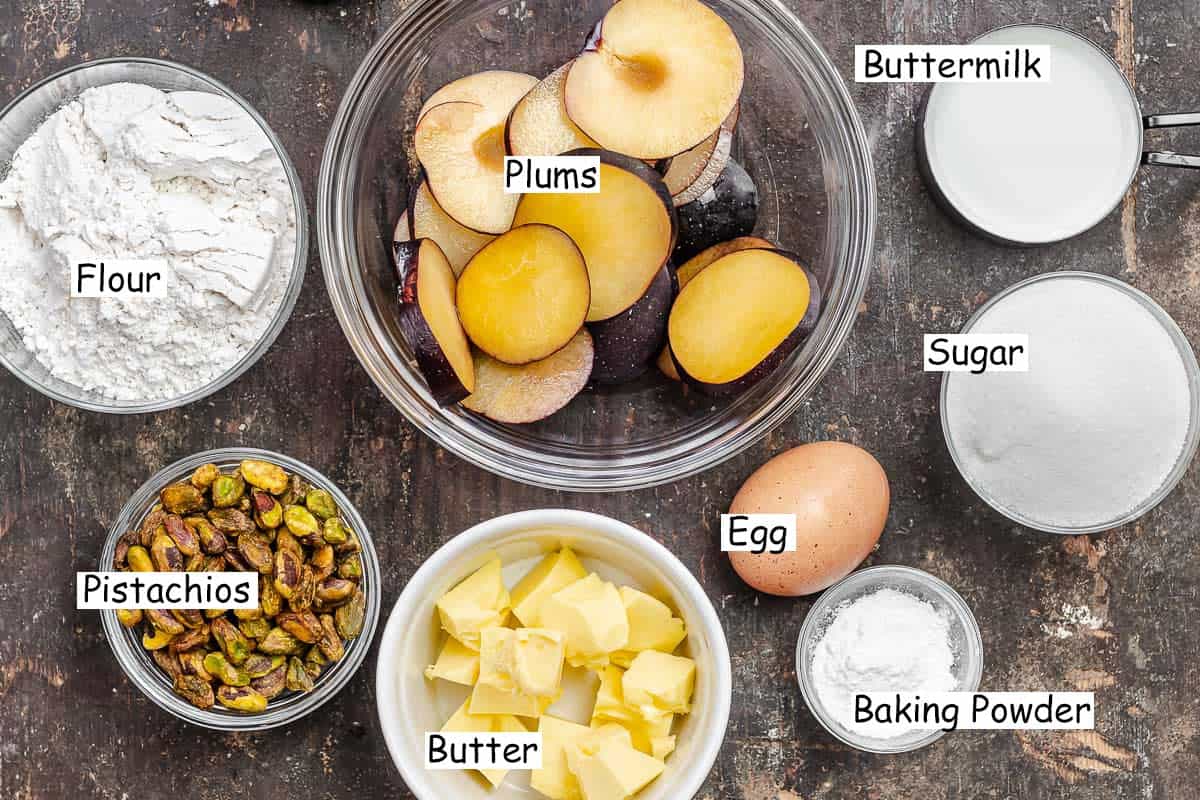 labeled ingredients for plum cake including buttermilk, lour, sugar, salt, yeast, pistachios, butter, egg, and sliced plums.