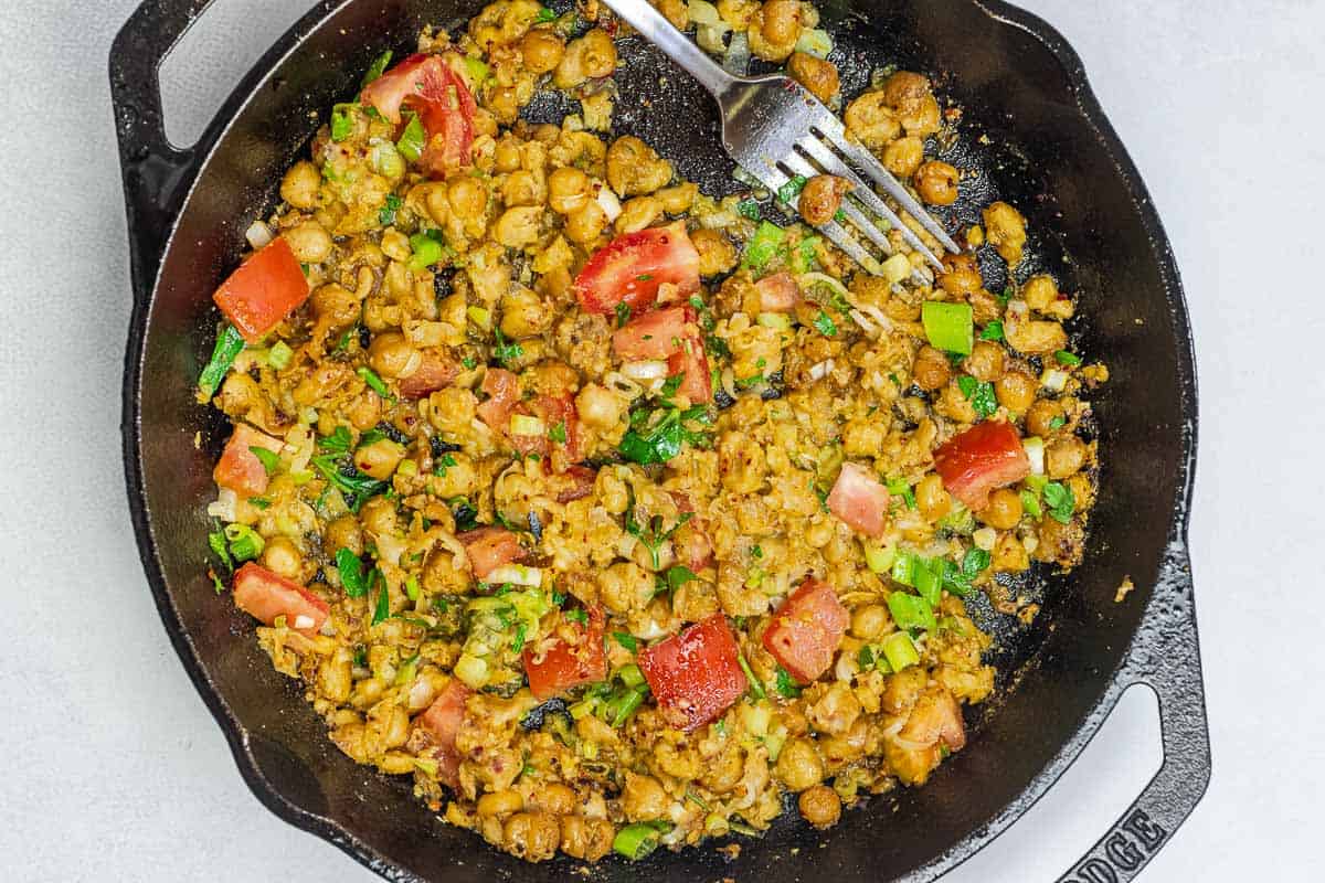 chickpeas in a skillet with tomato, green onions, and more.