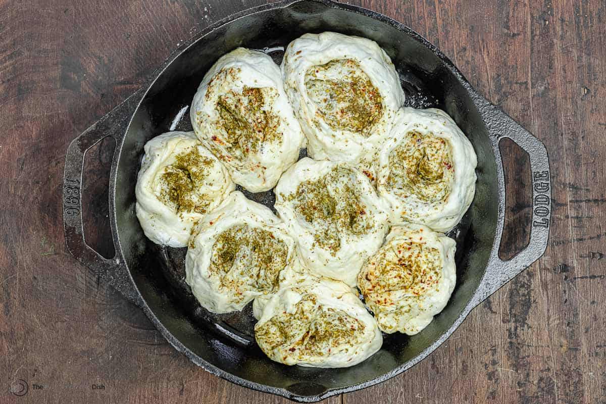 za'atar bread rolls in a skillet after being left to rise.