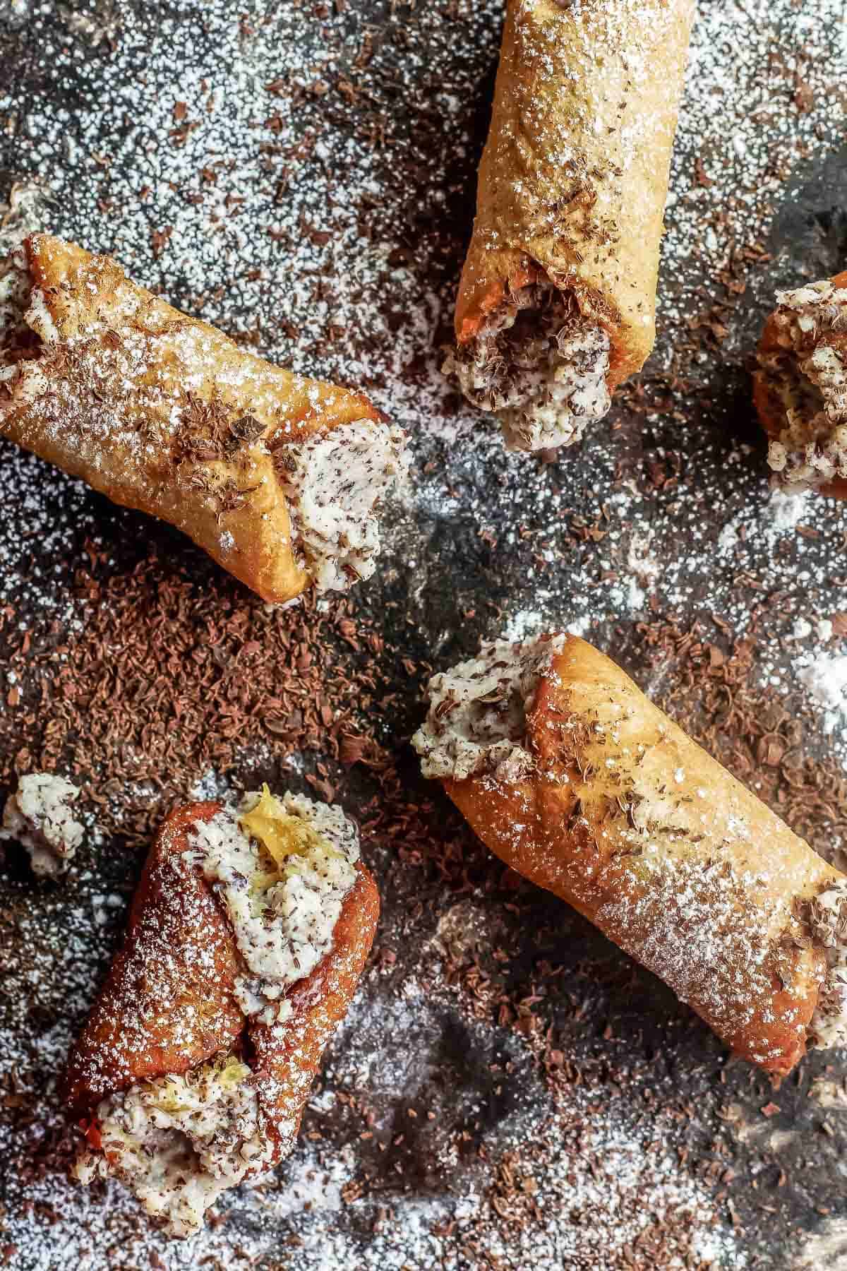 several cannoli dusted with powdered sugar and finished with grated chocolate.