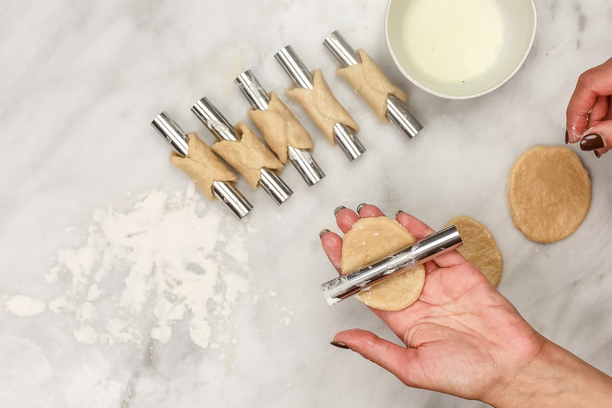 placing dough on cannoli molds.