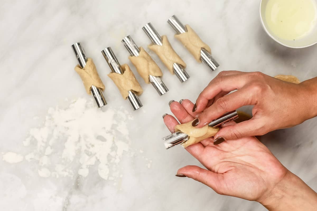 placing dough onto cannoli forms.