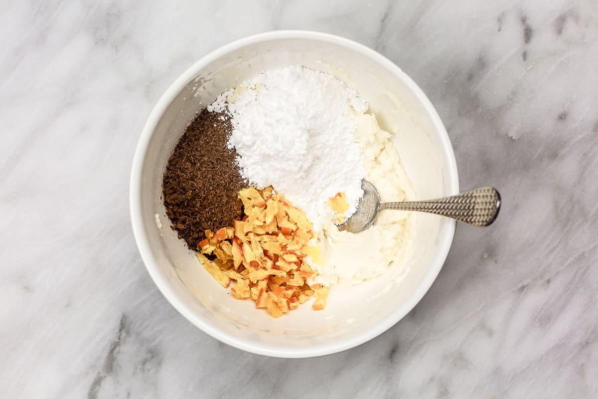 ingredients for cannoli filling including sugar, ricotta, candied orange, and grated chocolate.