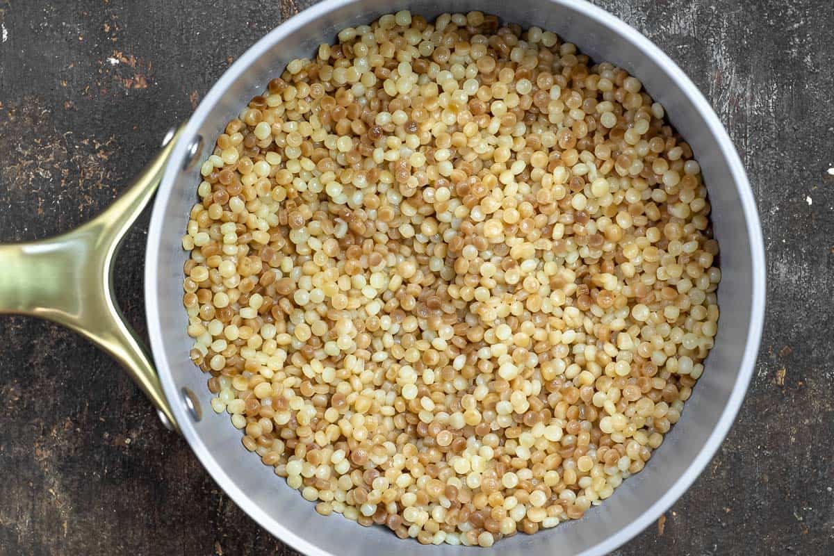 Cooked pearl couscous in a skillet.