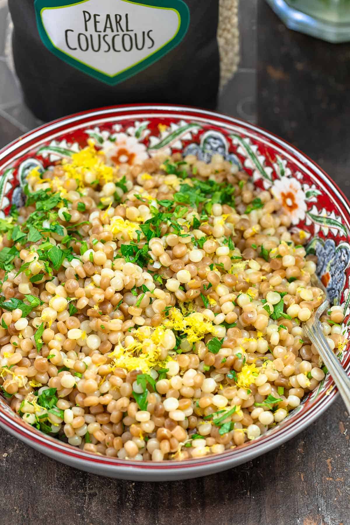 Pearl couscous in a bowl with a bag of The Mediterranean Dish Pearl Couscous in the background.