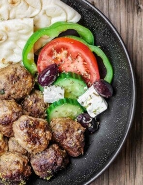 Greek meatballs recipe in a dinner bowl with salad and pita.