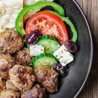 Greek meatballs recipe in a dinner bowl with salad and pita.