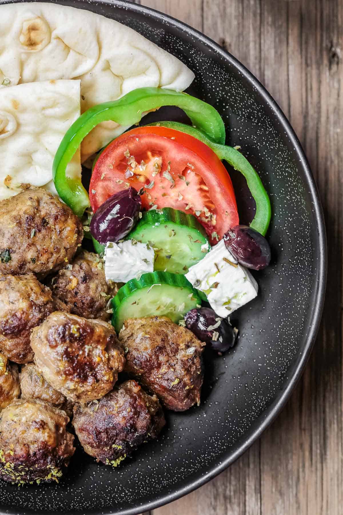 Greek meatballs recipe in a dinner bowl with salad and pita.