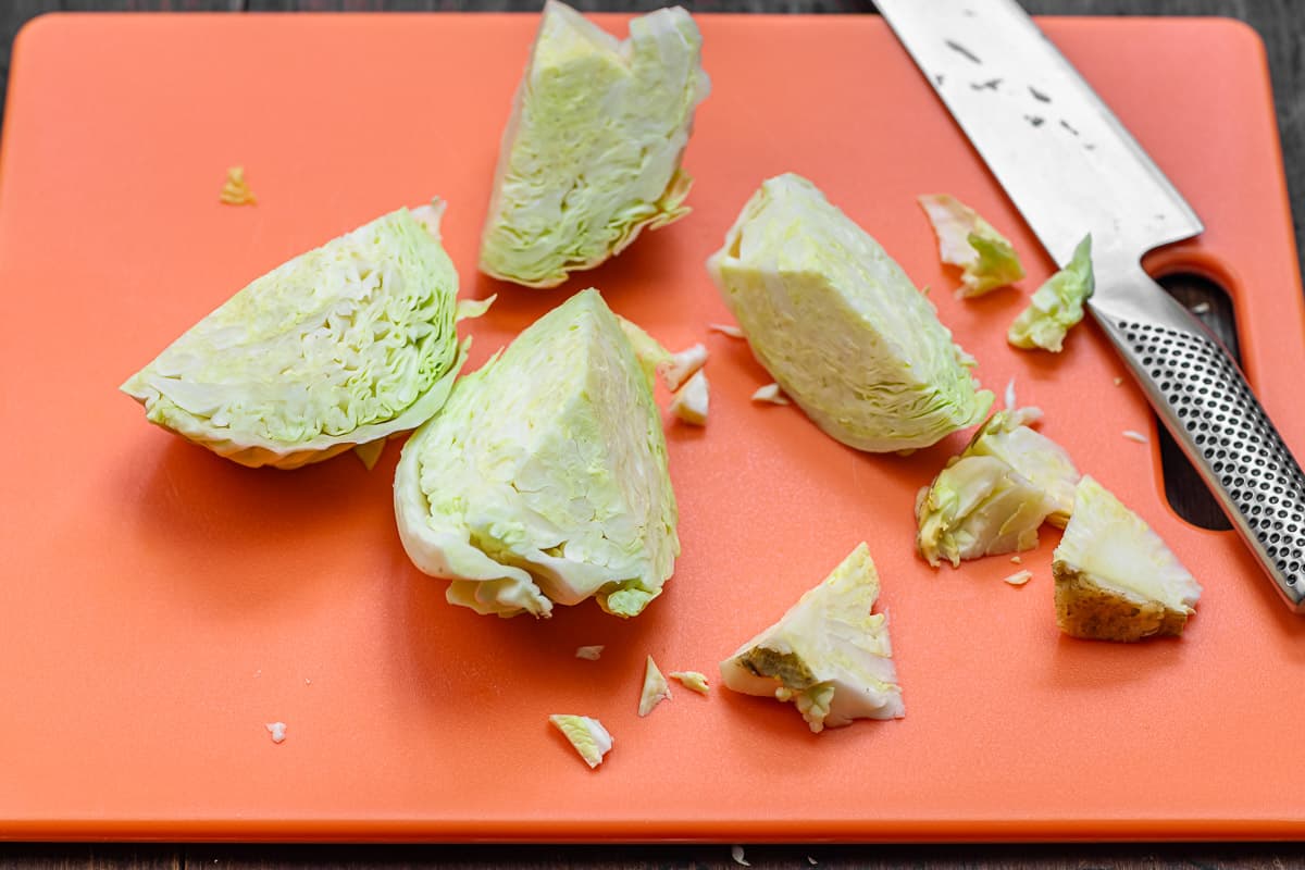 cabbage cut into wedges on an orange cutting board.