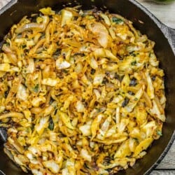 sauteed cabbage in a cast iron skillet with lime on the side.