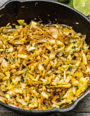 sautéed cabbage in a skillet with lime in the background.