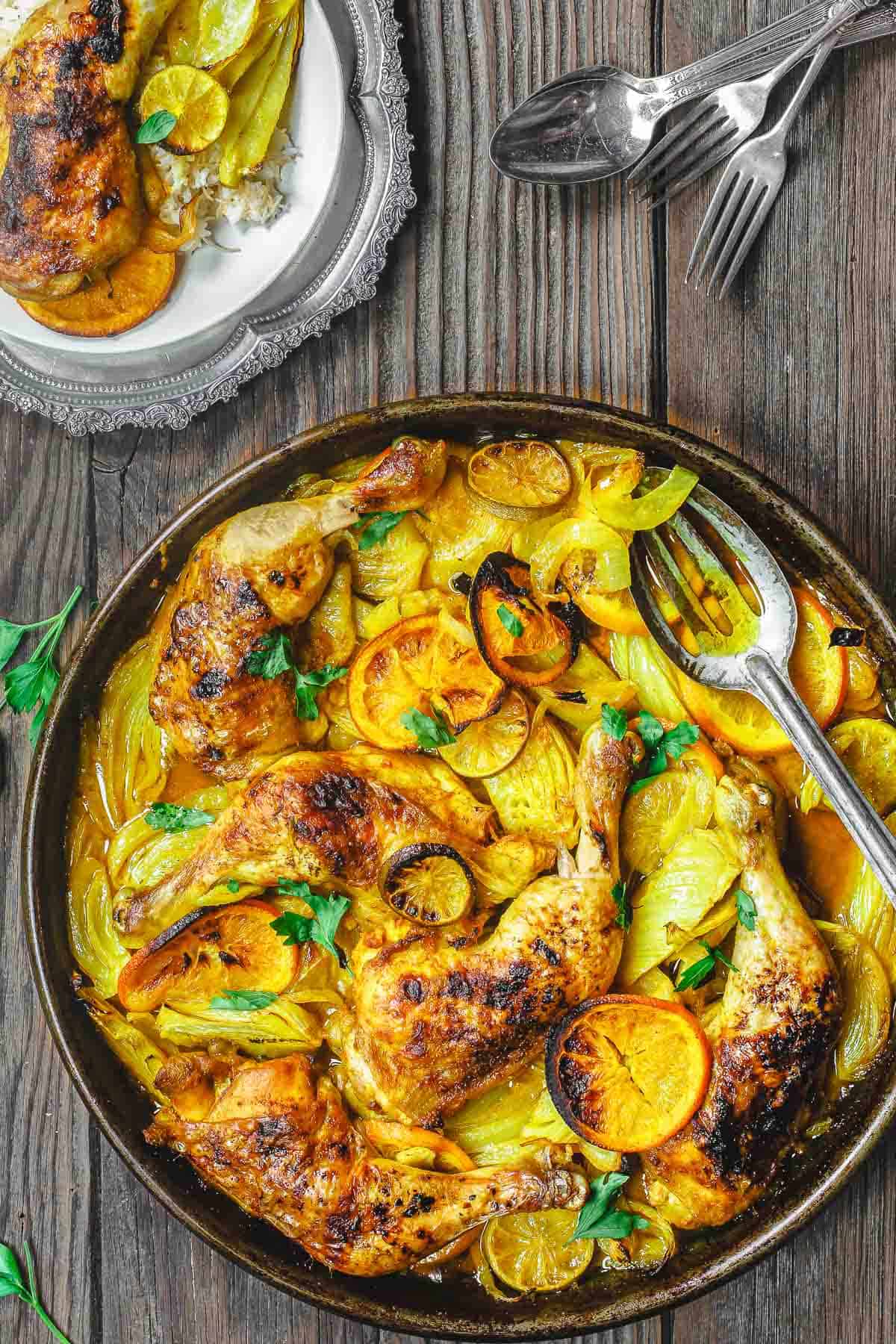 turmeric chicken leg quarters on a wooden table, with a plate of chicken to the side.