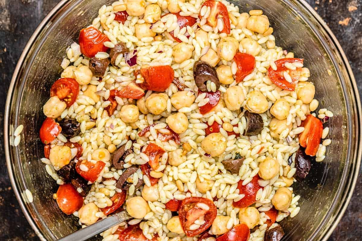 close up of vegetarian filling for stuffed peppers in a bowl with orzo, chickpeas, olives, and cherry tomatoes.