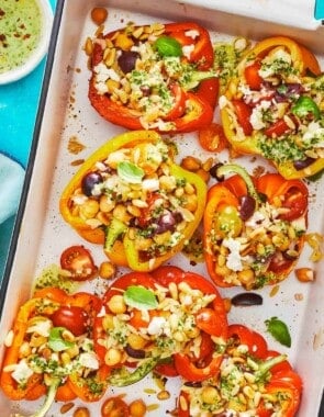 roasted vegetarian stuffed peppers on a large serving dish with a sprinkle of feta cheese.