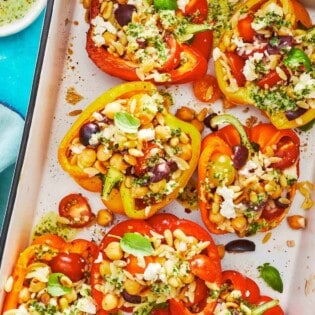 roasted vegetarian stuffed peppers on a large serving dish with a sprinkle of feta cheese.
