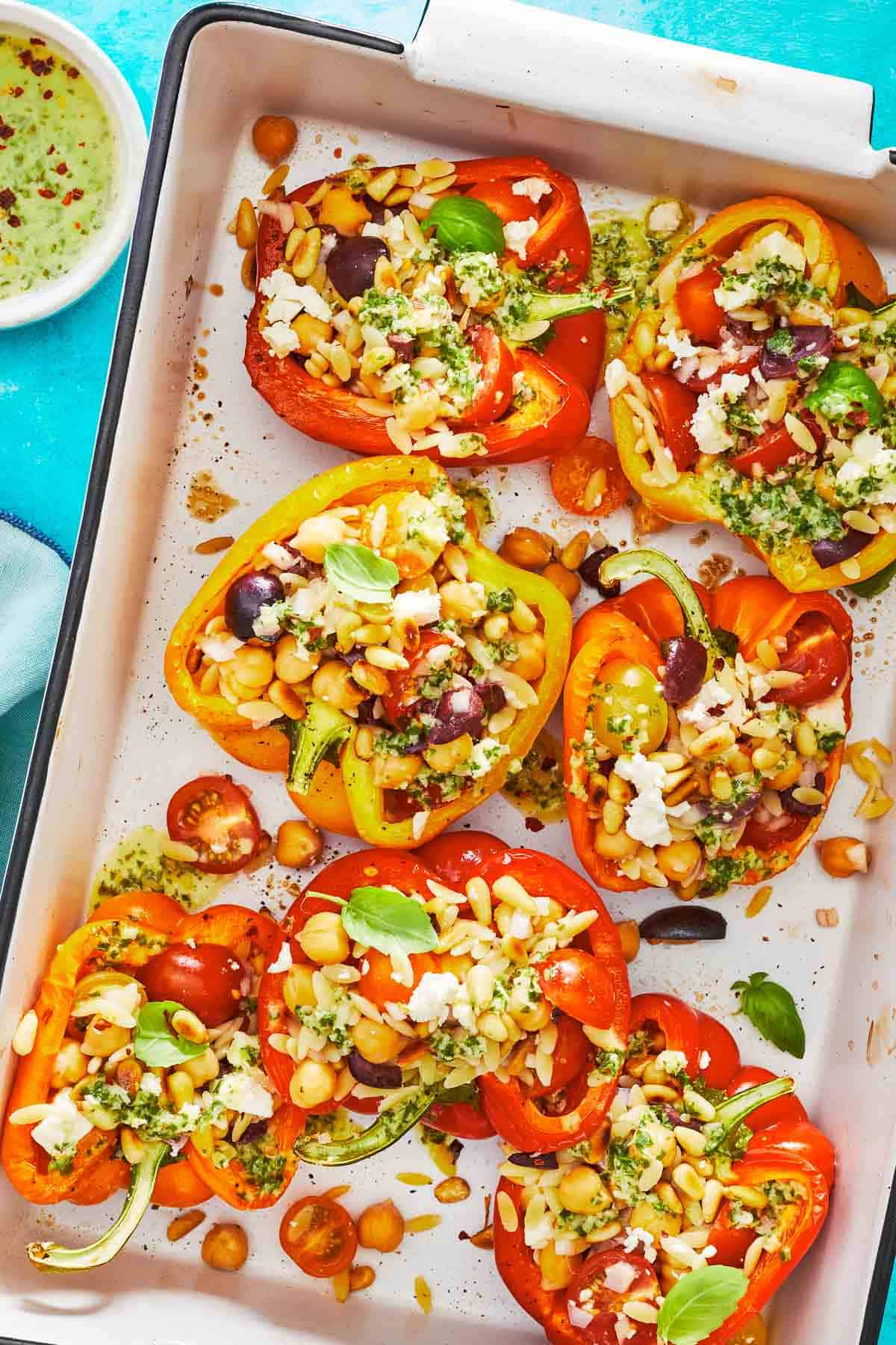 roasted vegetarian stuffed peppers on a large serving dish with a sprinkle of feta cheese.