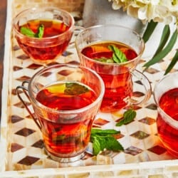 4 cups of Arabic tea with mint leaves on a tray.