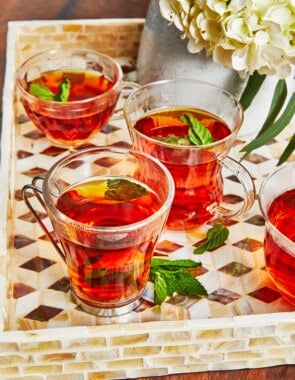 4 cups of Arabic tea with mint leaves on a tray.