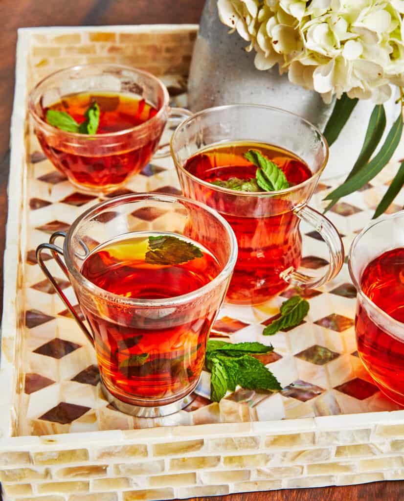 4 cups of Arabic tea with mint leaves on a tray.