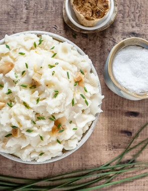 A bowl of mashed potatoes with roasted garlic, salt and chives