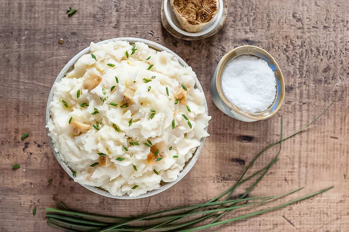 A bowl of mashed potatoes with roasted garlic, salt and chives