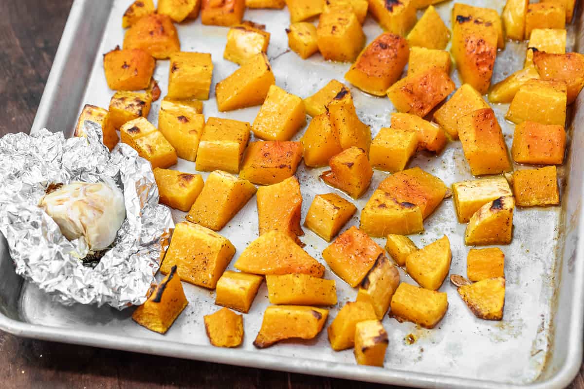 roasted butternut squash and roasted garlic on a sheet pan.