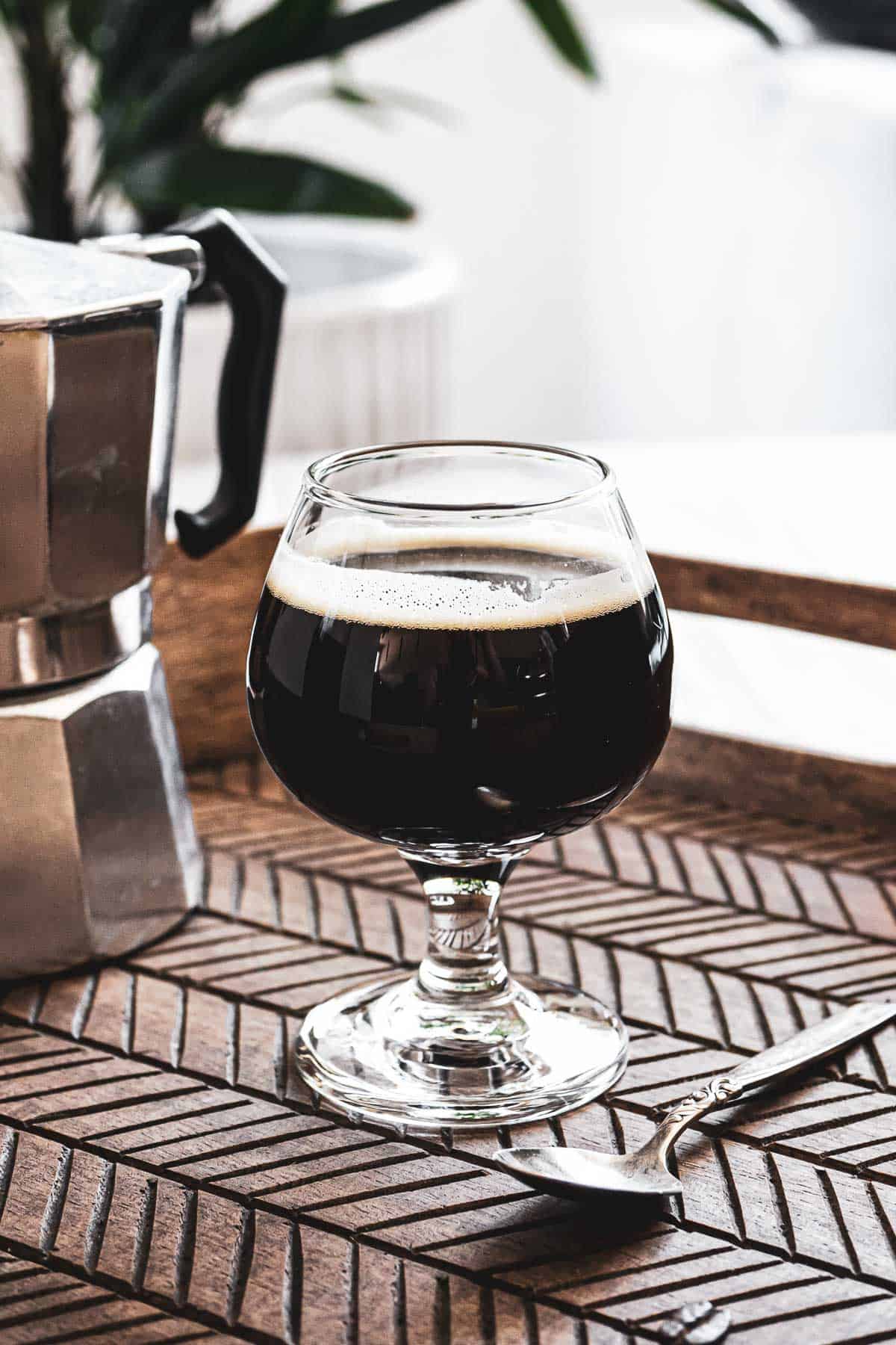 Spanish spiked coffee on a wooden tray next to a Moka pot.