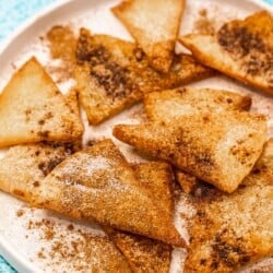 churro chips on a plate dusted with cinnamon and sugar.