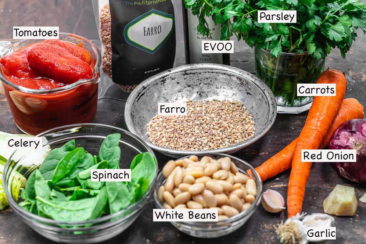 labeled ingredients for farro soup including farro, parsley, carrots, onion, parmesan rind, garlic, white beans, spinach, and olive oil.