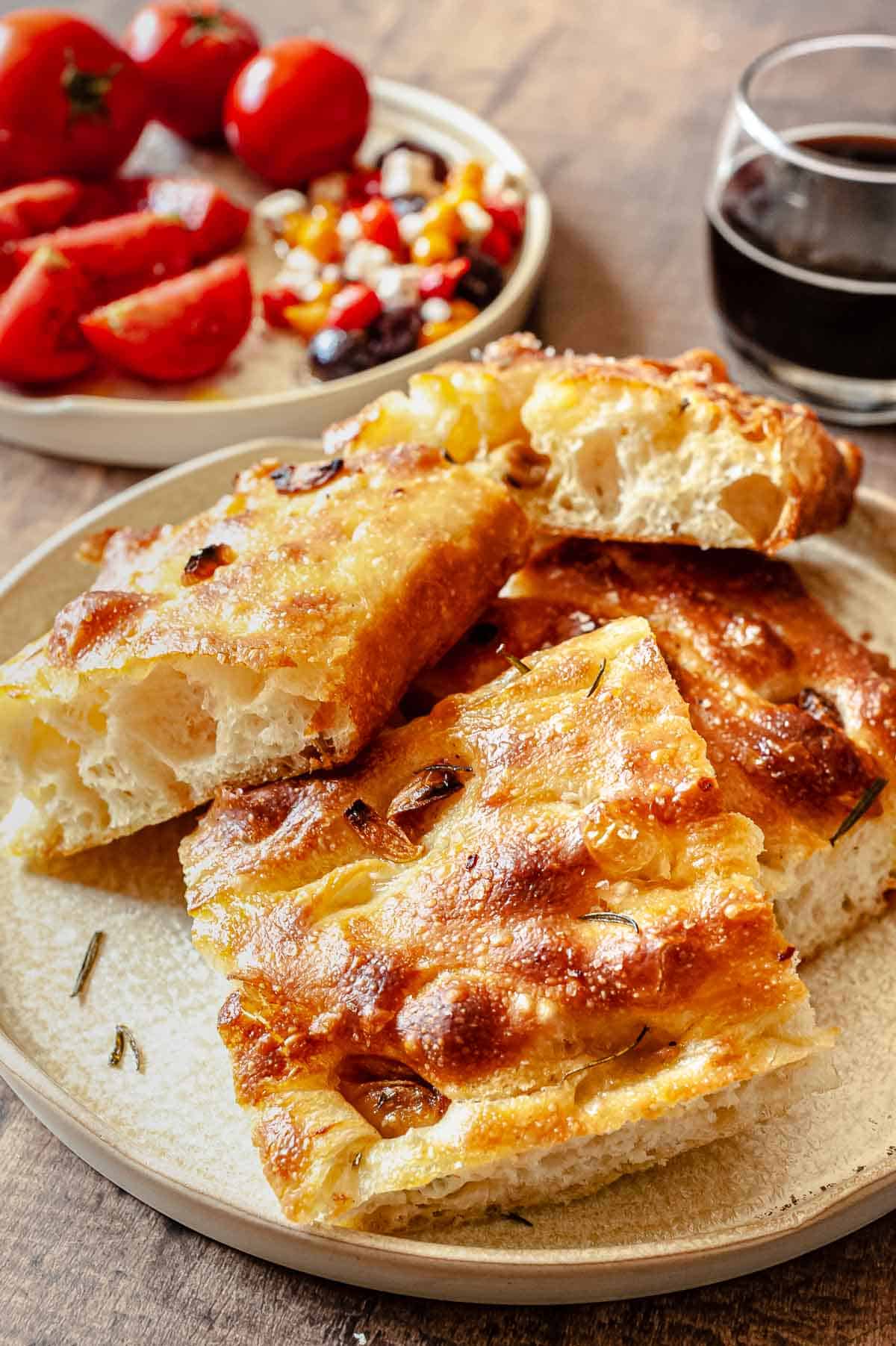 focaccia with tomatoes and a drink in the background.