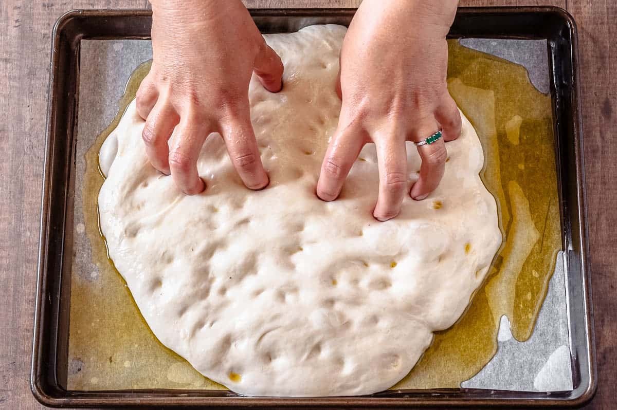 adding dimples to focaccia bread dough.