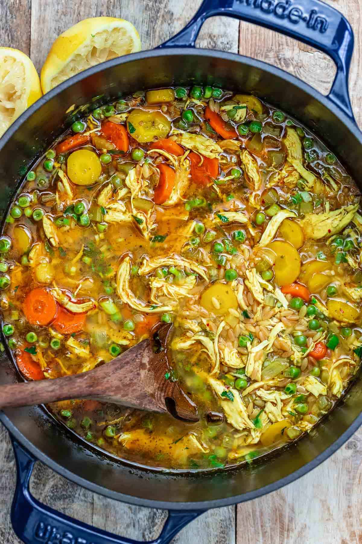 Lemon orzo chicken soup cooking in a pot with a spoon.