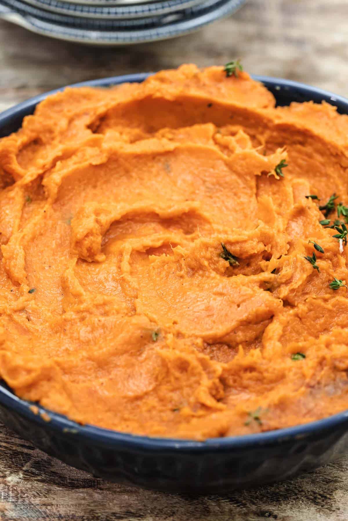 mashed sweet potatoes with garlic and thyme in a blue bowl.