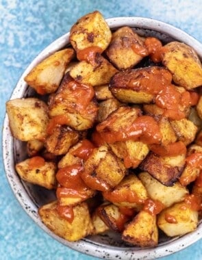 patatas bravas in a bowl with salsa brava drizzled on top.