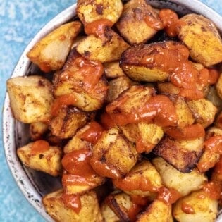 patatas bravas in a bowl with salsa brava drizzled on top.