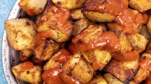patatas bravas in a bowl with salsa brava drizzled on top.